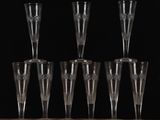 six empty champagne flutes lined up on a table against a black background
