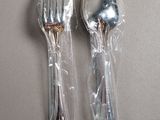 two forks and spoons wrapped in plastic on a table