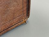 une mallette en cuir marron munie d'une poignée, posée sur une table