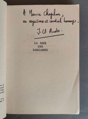 un livre ouvert, sur lequel figure une citation manuscrite, posé sur une table