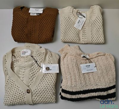 Quatre pulls sont alignés sur une étagère, avec leurs étiquettes encore attachées.