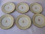 six assiettes dorées et blanches ornées d'un ours, posées sur une table