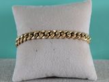 gros plan d'un bracelet en chaîne en or sur un oreiller