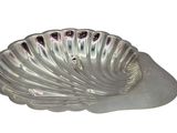 a silver shell shaped dish on a white surface