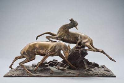 une sculpture en bronze représentant deux cerfs courant sur un rocher