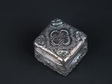 a small silver box with a design on the lid