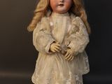 an old fashioned doll with blonde hair and a white dress