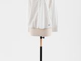 une chemise blanche posée sur un mannequin, devant un fond blanc