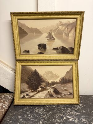 deux photos encadrées représentant des montagnes et un lac, posées sur une table