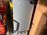 un petit réfrigérateur à côté d'une pile de cartons dans une pièce