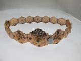 une image représentant un bracelet en or orné de pierres vertes sur un fond blanc