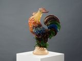 statue of a colorful rooster on a white pedestal against a gray background
