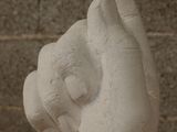a white statue of a hand holding something in it ' s right hand