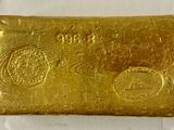 un lingot d'or est représenté sur une surface blanche