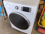 une machine à laver posée à côté d'une pile d'autres appareils électroménagers