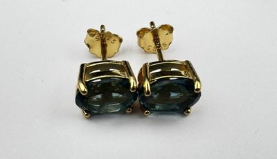 une paire de boucles d'oreilles en saphir bleu posées sur un fond blanc