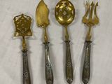 quatre cuillères en argent et en or et une fourchette posées sur une nappe blanche