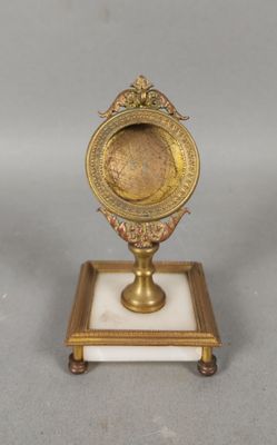une image représentant une petite horloge en laiton posée sur un socle en marbre