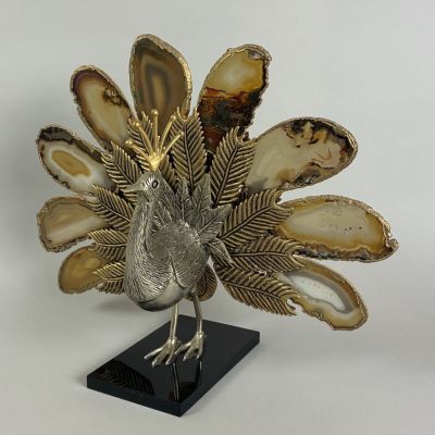 an image of a silver and gold peacock statue on a black stand