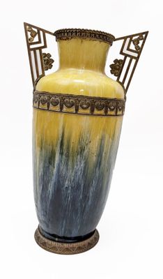 a yellow and blue vase sitting on a stand