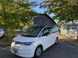 a small white van parked in a parking lot with a tent on top of it
