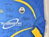 a framed picture of a blue and yellow shirt with autographs