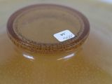 a brown vase with a label on it sitting on a table
