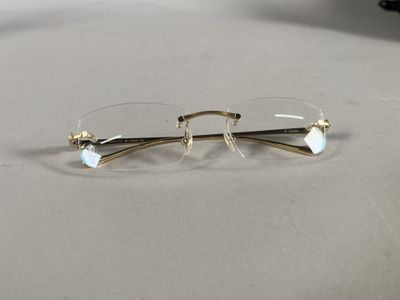 pair of glasses on a table with a laptop in the background