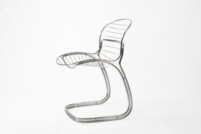 une chaise en métal posée sur une surface blanche