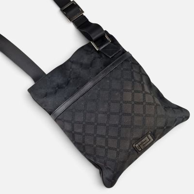 Le petit sac à bandoulière est noir et possède une bandoulière noire.