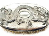 a silver plate with a dragon on it on a white surface