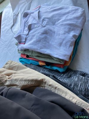 un tas de vêtements posé sur un lit près d'une fenêtre