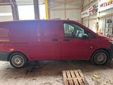 La camionnette rouge est garée dans un entrepôt où se trouvent des palettes au sol.