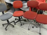 quatre chaises de bureau montées sur roulettes, disposées dans une pièce avec d’autres meubles de bureau