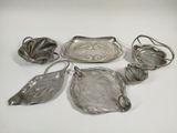 six silver plated dishes and spoons on a white surface