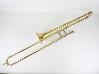 un trombone en laiton posé sur une surface blanche