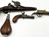 trois vieilles armes à feu sont exposées sur une surface blanche, devant un fond blanc