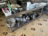 de nombreuses casseroles et poêles posées sur une table en acier inoxydable