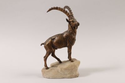 statue of a goat standing on a rock on a white background
