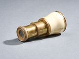 un télescope doré et blanc posé sur une surface grise