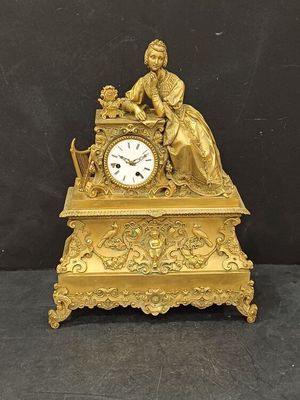 une horloge en or avec une femme assise dessus