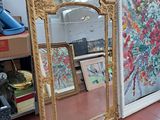 un grand miroir au milieu d'une pièce où est accroché un tableau au mur