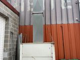 a white refrigerator sitting outside of a building next to a green trash can