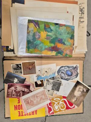 une valise remplie d'œuvres d'art et de papiers posée par terre