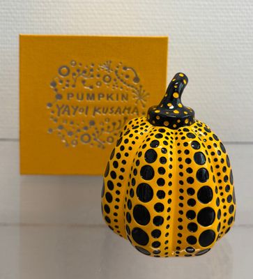 a yellow and black pumpkin sitting next to a yellow box
