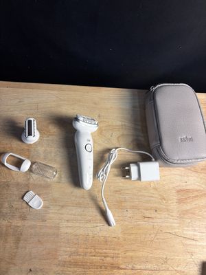 un rasoir électrique blanc posé sur une table, à côté d'autres objets
