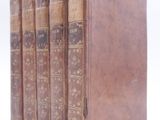 three old books are stacked on top of each other on a white surface