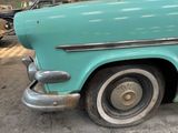 a blue car parked in a garage with other cars in the background