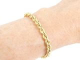 the woman is wearing a gold bracelet with a chain on her wrist