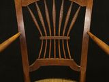 the back of a wooden chair with a woven seat
